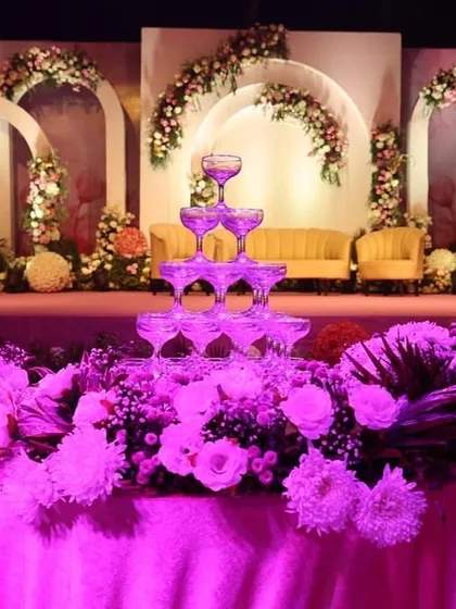 A closer look at the champagne tower and floral arrangements on the main stage. The vibrant purple lighting adds a touch of modern glamour to the classic romantic setup, highlighting the beautiful details.
