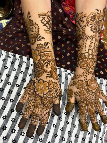 A unique bridal design that combines traditional motifs with modern spacing. The patterns flow from the palm up the arm, creating a cohesive and artistic statement.