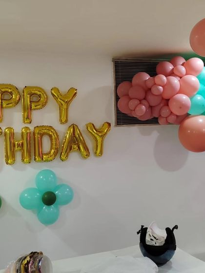 A detailed shot of the 'Happy Birthday' foil balloons and the organic balloon cloud on the wall, highlighting the soft, earthy color palette of this dinosaur-themed celebration.