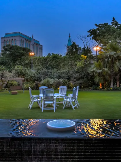An elegant water feature serves as the tranquil foreground to a lush residential lawn. The gentle bubbling fountains add soothing sound and movement, perfectly complementing the serene evening ambiance and creating an ideal space for relaxation.