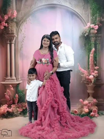 A complete family portrait, with their son standing proudly beside them. The pink and floral theme creates a soft and loving atmosphere.