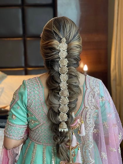 A beautiful, intricate braid with golden accessories woven through it. This is a modern take on the traditional parandi, perfect for a bride who wants a unique and statement making hairstyle.