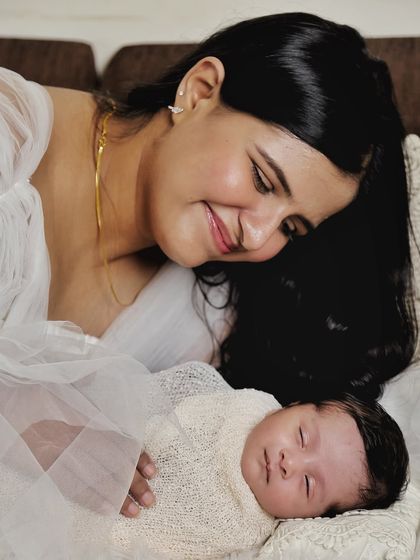 A quiet moment between mother and child. Her gentle smile as she looks down at her sleeping baby tells a story of deep love and contentment.