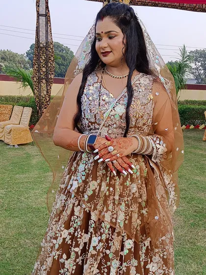 A client showing off her henna-adorned hands while wearing the brown floral lehenga.