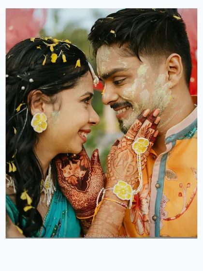 A close-up of the couple sharing a sweet moment amidst the haldi celebrations, their hands adorned with beautiful floral jewelry.