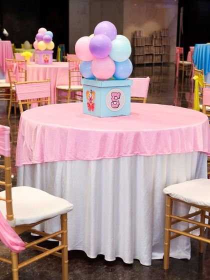 A beautifully decorated table setting with a pink tablecloth, matching chair sashes, and a themed centerpiece.