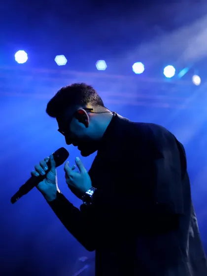 A silhouette against the stage lights tells a story of its own. In these quiet, moody moments, the artist's form becomes an iconic symbol of the music.