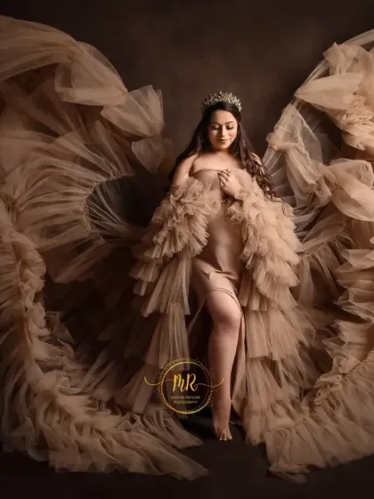 A stunning solo maternity portrait in a flowing beige gown. The ruffled fabric creates a beautiful wing shape, highlighting the angelic theme of this fine art pregnancy photo.