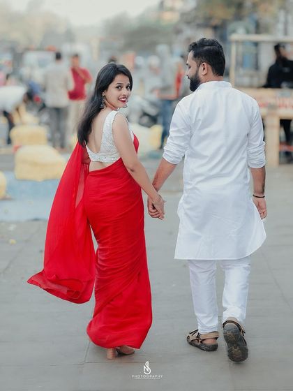 A beautiful "follow me" shot, with her vibrant red saree creating a stunning visual as they walk through the city.