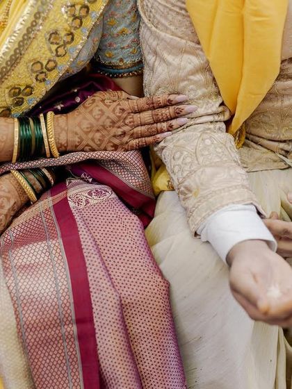 A close-up of hands during the ceremony. The bride's hand, adorned with henna and green bangles, rests gently on the groom's arm. It’s a small detail that speaks of tradition, connection, and comfort.