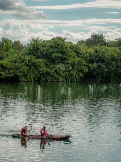 A couple enjoys a peaceful kayaking session, paddling together against a backdrop of beautiful trees.