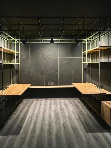 In a compact micro-studio in Hauz Khas, we used a bold green metal framework for desks and shelving against a dark, moody palette to create a functional and expressive workspace within a very small volume.