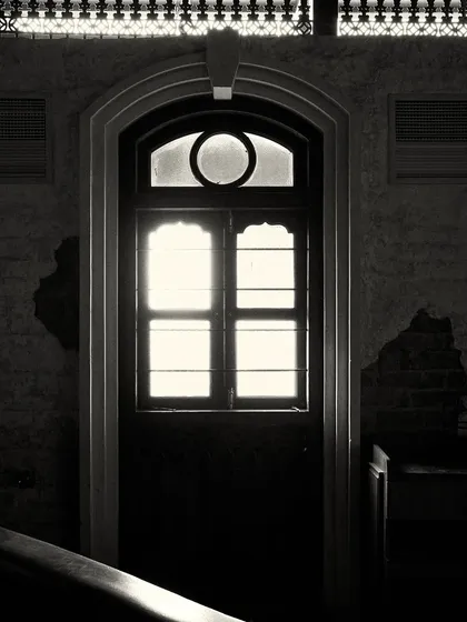 An arched doorway with a transom window, backlit to create a strong silhouette. This architectural detail is repeated throughout the space.