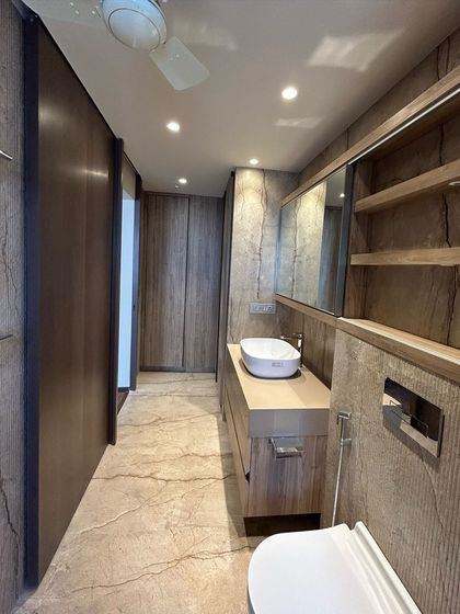 A glimpse from a site visit of a bathroom nearing completion. The space uses a pared-down, neutral palette with wood-grain textures and clean lines to create a serene and calming environment.