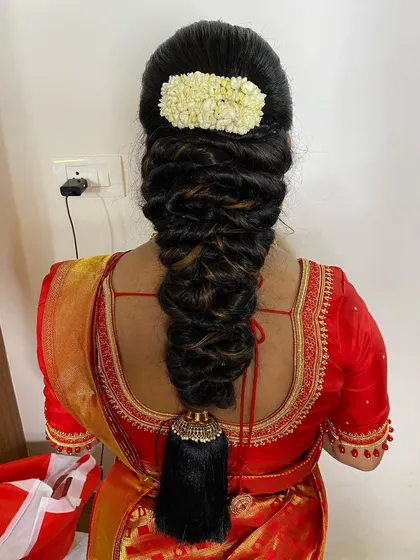 A close-up of a voluminous messy braid, adorned with a jasmine gajra. The highlights in the hair add dimension to this beautiful and textured hairstyle.