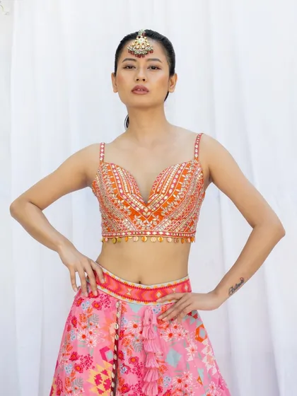 A clean, front-facing shot from a fashion lookbook, designed to clearly display the details of the embroidered blouse. The bright, even lighting ensures that the colors are true to life and every element of the garment is visible.
