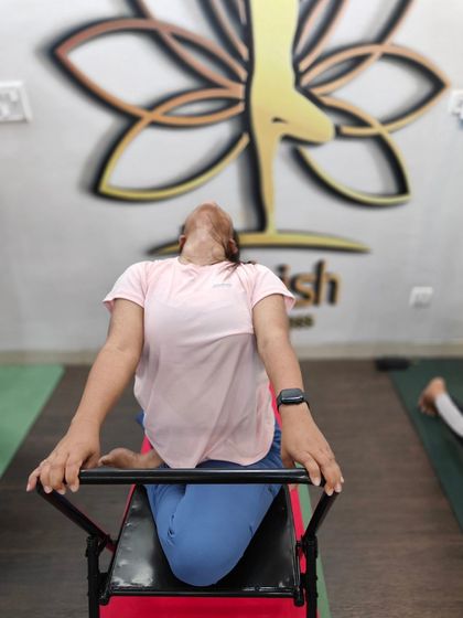 A student uses a specialized back-bending bench to safely open the thoracic spine.