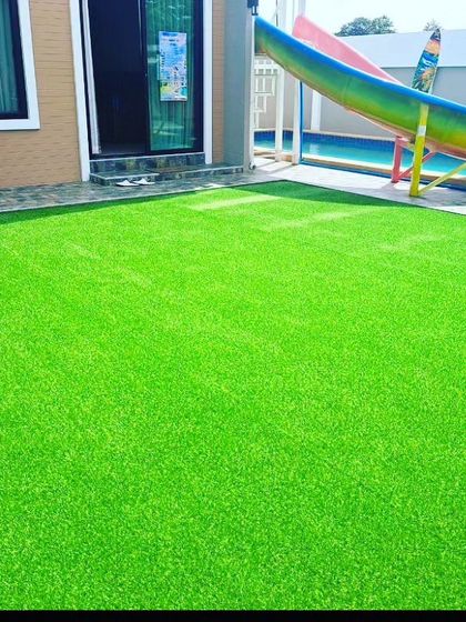 A vibrant green artificial lawn installed next to a home swimming pool. This material is a safe, non slip alternative to tiles and stays clean without getting muddy.