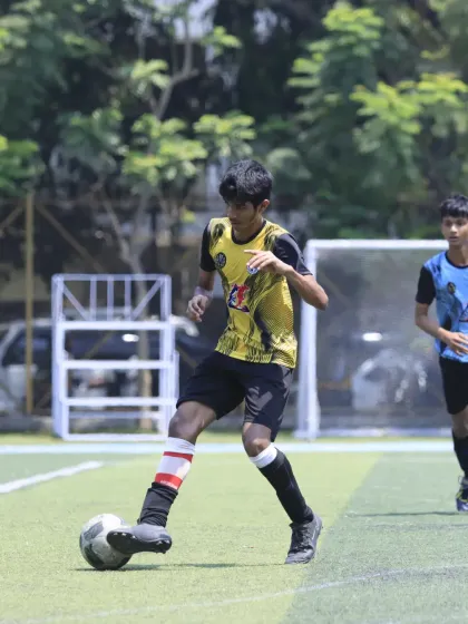 A player in full control, dribbling the ball with his head up to assess his options. This demonstrates the vision and game awareness we teach.