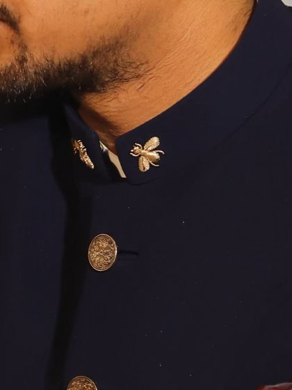 The smallest details matter. This close-up shows the custom bee-shaped collar pins and ornate buttons that add a unique and personal touch to the sherwani.