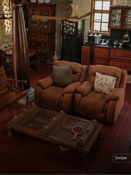 The living area is furnished with comfortable, modern recliners alongside traditional wooden furniture, showing how contemporary comfort can be integrated into a heritage-inspired space.