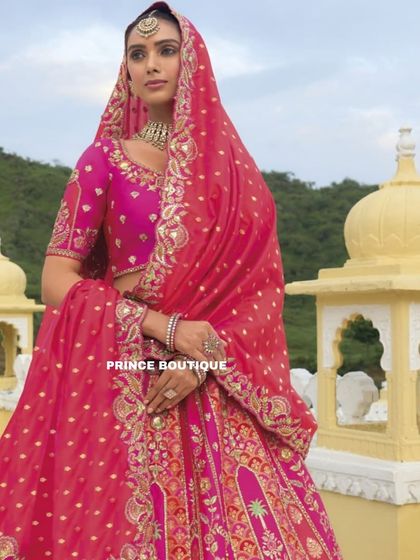 A regal pose in the pink and orange bridal lehenga, with the dupatta elegantly draped over the head. This showcases the complete, traditional bridal look.