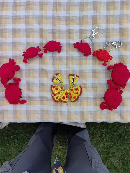A fun layout of my crab and pizza slice pins and keychains on my market stall cloth. It shows how they can be arranged as a fun collection.