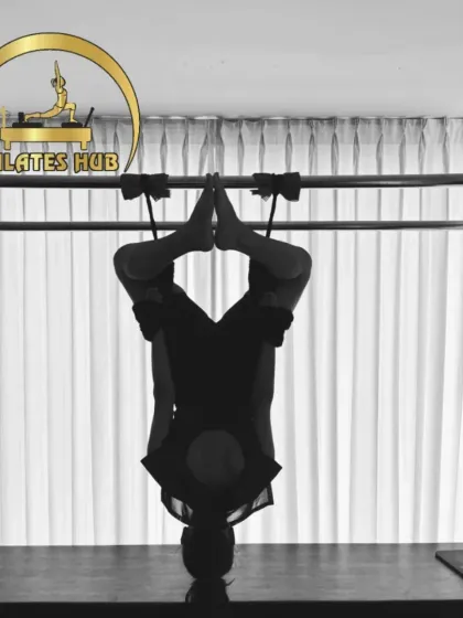 This is an artistic shot of an inversion on the Cadillac. It highlights the blend of strength, control, and flexibility that is at the heart of advanced Pilates work.