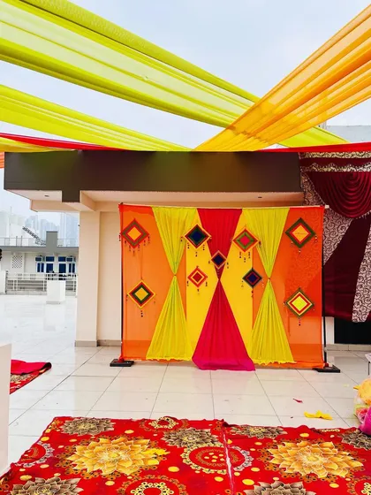 A simple backdrop with colorful drapes and hangings set up on a rooftop. Even a small space can be made ready for a beautiful Haldi ceremony.