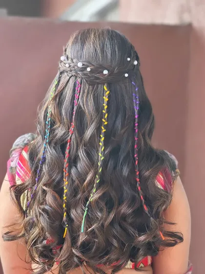 A carnival-ready hairstyle with a braided crown, loose waves, and colorful threads woven through.