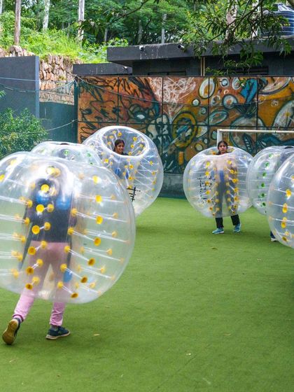 A team gets ready for Bubble Soccer, standing inside their inflatable bubbles against a backdrop of cool graffiti art.