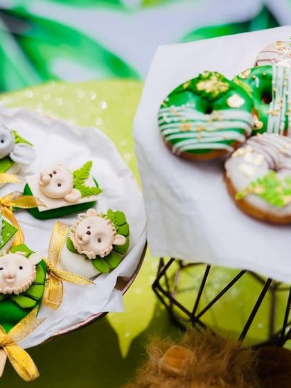 Themed desserts for a safari party, including donuts with green icing and cakesicles decorated with adorable fondant animal faces.
