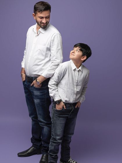 A father and son look at each other with admiration. This simple, candid pose perfectly captures the special bond they share.