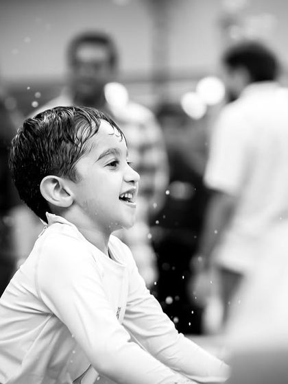 A black and white shot capturing a moment of pure happiness. Even without color, the joy of a child splashing in the water is palpable.