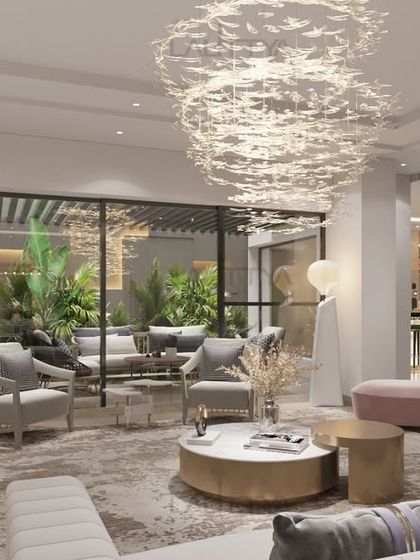 This living room is designed for both beauty and comfort. The curved blush sofa creates a cozy seating area, complemented by plush quilted benches and elegant armchairs. Sculptural side tables and layered textures bring depth to the space.