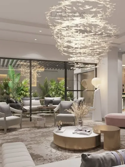 A living room concept designed for comfort and beauty. A curved blush sofa creates a soft, inviting seating area, complemented by elegant armchairs and sculptural side tables. Metallic accents and layered textures add depth and a touch of glamour.