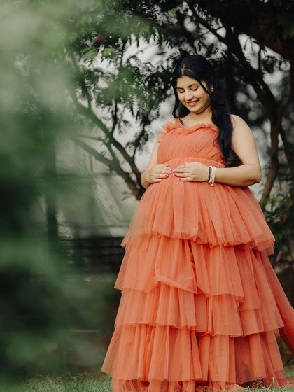 A serene solo shot of the mom-to-be, cradling her baby bump. The soft tulle fabric of the gown looks beautiful against the natural backdrop.