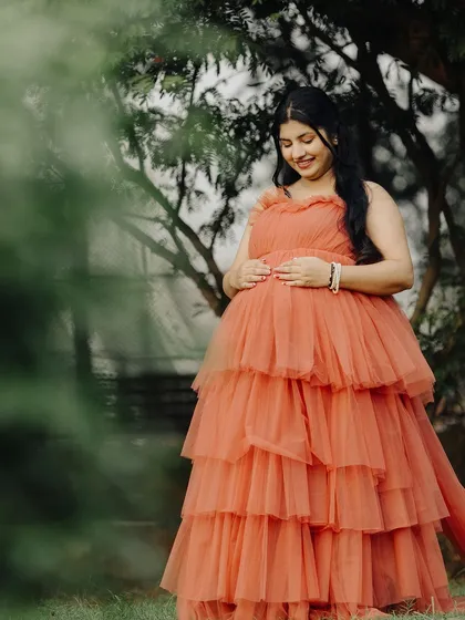 A serene solo shot of the mom-to-be, cradling her baby bump. The soft tulle fabric of the gown looks beautiful against the natural backdrop.