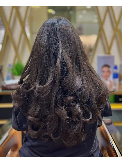 This is another example of a beautiful layer cut on long hair, styled with soft curls to enhance the texture and movement of the layers.