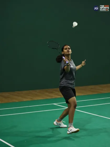A badminton player in mid-action, showcasing the agility and focus honed in our state-of-the-art indoor courts under the guidance of expert coaches.