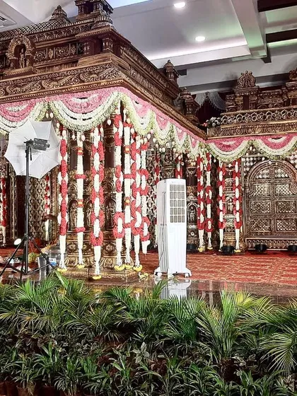 This is one of our grand, temple-style muhurtham stages. The intricate gold structure, combined with traditional red and white flower garlands, creates an opulent and divine setting inside a convention hall.