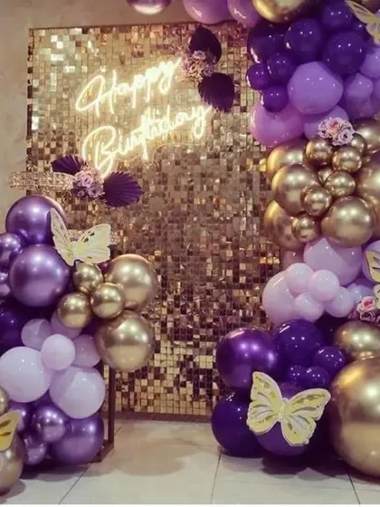 A luxurious gold and purple butterfly-themed decoration with a gold sequin wall and a "Happy Birthday" neon sign.
