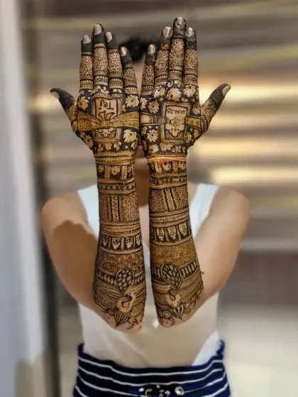 A full view of a traditional bridal mehendi with peacocks on the wrists and the couple's initials hidden within the intricate patterns on the palms.