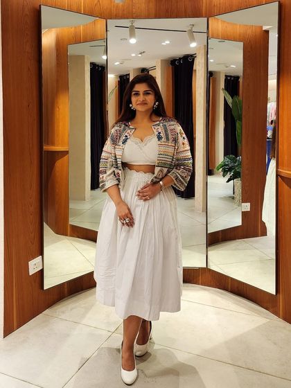 An all-white fusion look featuring a bralette, a flowing skirt, and a stunningly embellished jacket. This outfit is an ode to Indian traditions woven with contemporary style.