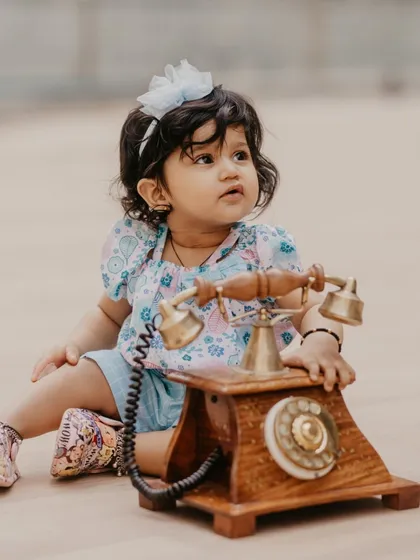 A curious little girl interacting with a vintage rotary telephone prop during her indoor milestone session.