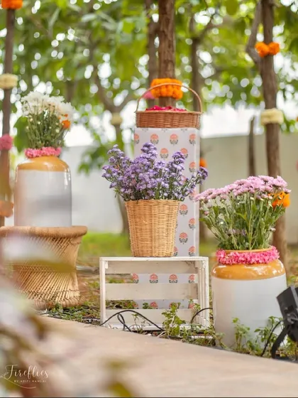 A corner arrangement of flowers in rustic cane baskets and ceramic vases, adding to the traditional, handcrafted feel of the event.