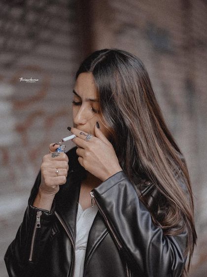 A moody and edgy urban portrait. The action of lighting a cigarette adds a cinematic and narrative quality to the image, perfect for a more conceptual street style shoot.