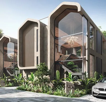The facade of the Vagator Villas features soft, curved openings and large glass walls that create a distinctive, modern typology. The surrounding tropical foliage is an integral part of the design, softening the building's edges and grounding it in its location.