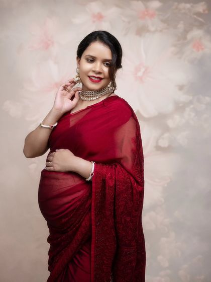 Every detail in this shot tells a story of elegance and motherhood. This gorgeous mom-to-be in a red saree is pure magic.