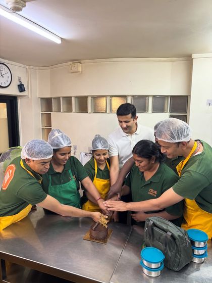 We are all in this together. Our team cutting our anniversary cake, a sweet moment shared by the people who make True Tiffins possible.